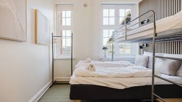 A bunk bed room with a window, a wall-mounted lamp, and a framed picture.