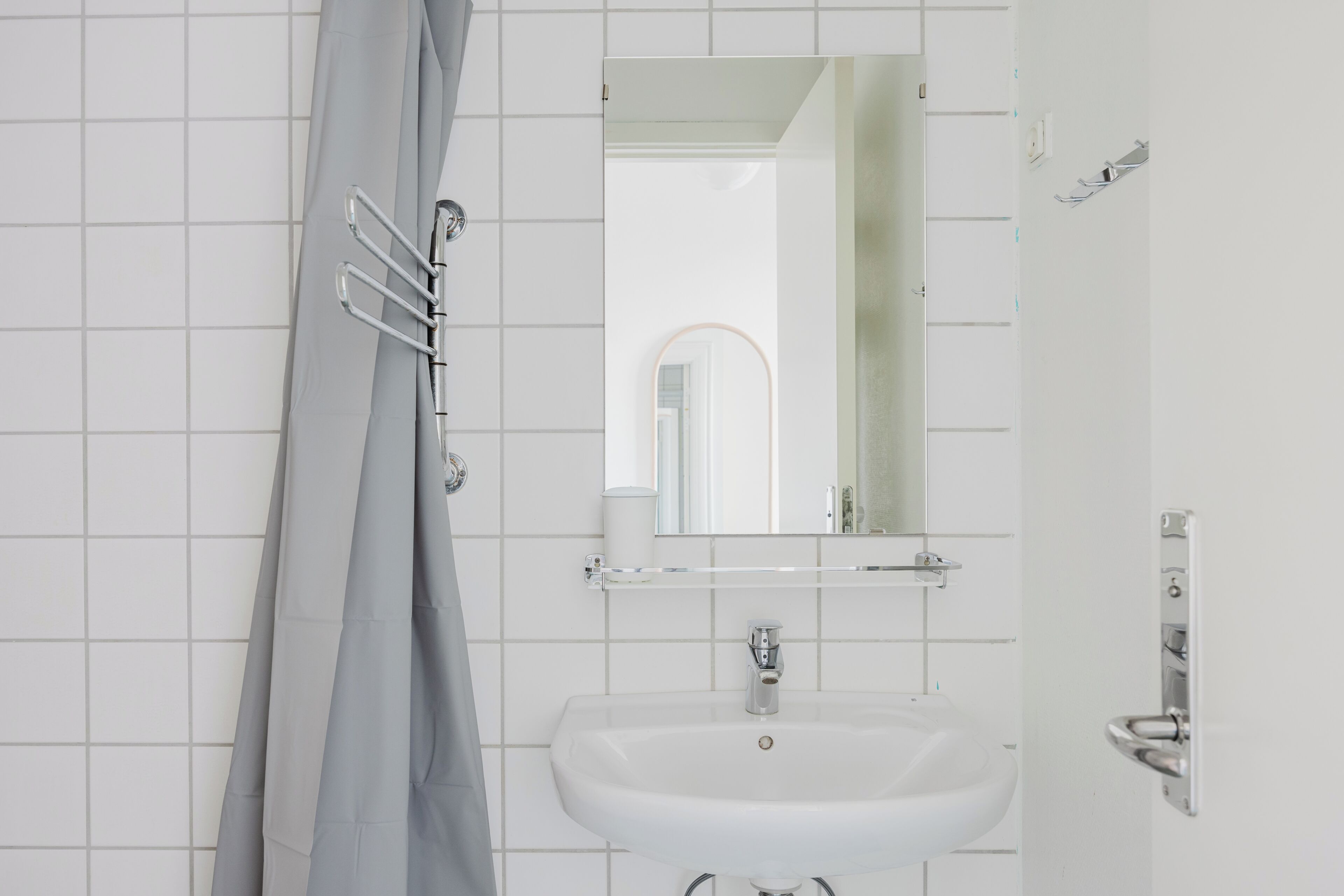 Ein Badezimmer mit Waschbecken, Spiegel und Duschvorhang.