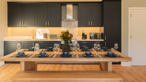Une cuisine moderne avec des meubles de couleur sombre, un îlot central agrémenté de vaisselle bleue et un vase rempli de fleurs.