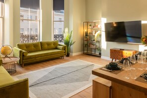 A modern living room with a green sofa, a wooden coffee table, and a flat-screen TV mounted on the wall. - Host Stay The Georgian Quarter Catherine Street VI (Liverpool)