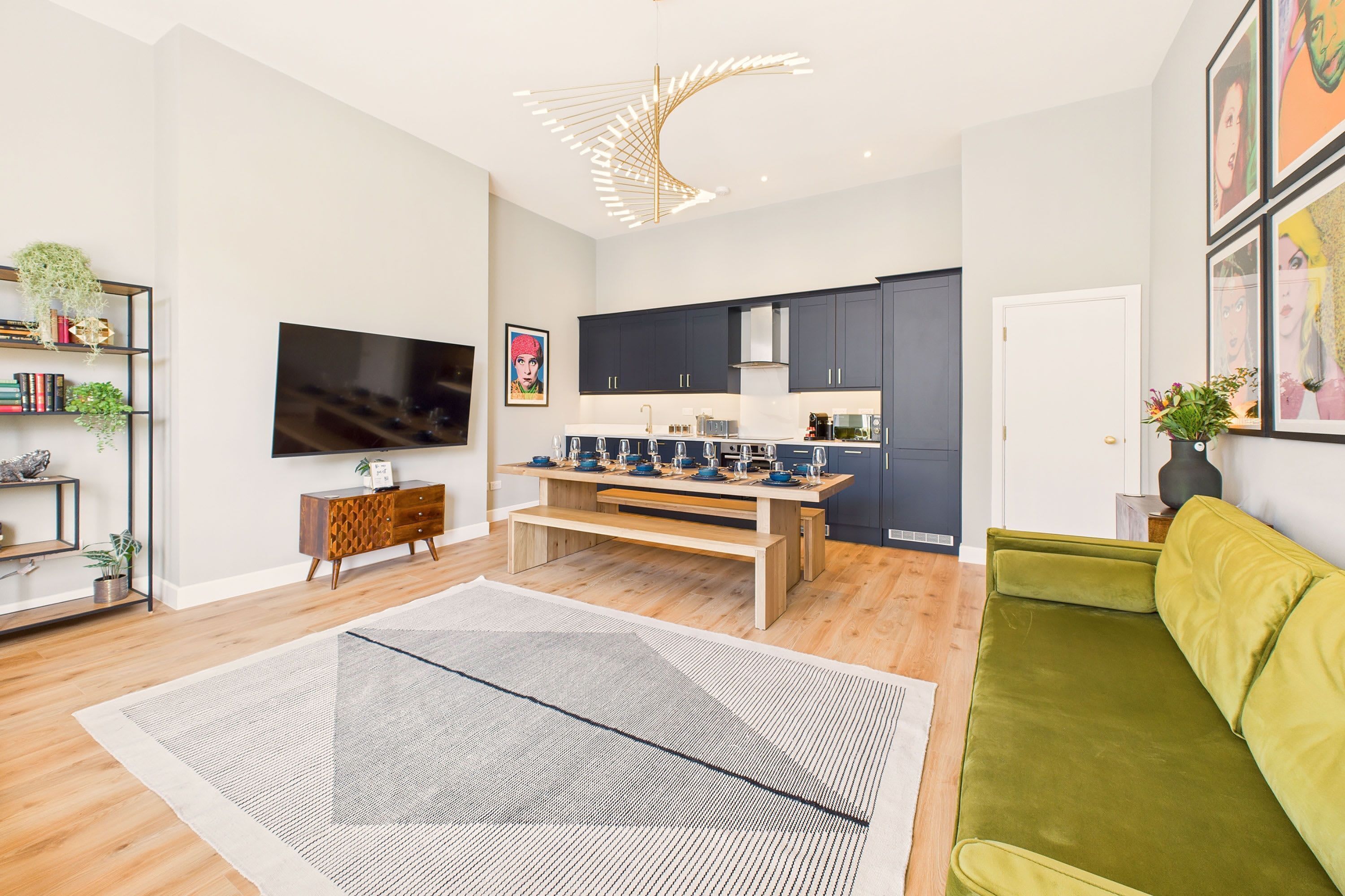 A modern living room with a TV, wooden coffee table, and a green sofa.
