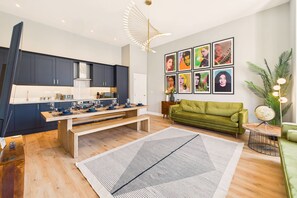 A modern kitchen with dark cabinets, a wooden dining table, and a green sofa in a living area with a large rug. - Host Stay The Georgian Quarter Catherine Street VI (Liverpool)