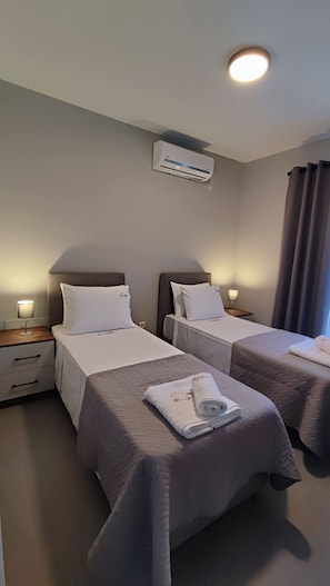 A hotel room with two beds, each with a nightstand, a lamp, and a wall-mounted air conditioner. - Alaia Haven Elegant Holiday Home in Kefalonia (Kefalonia)