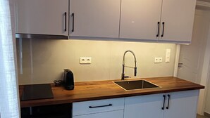 Eine moderne Küche mit weißen Schränken, einer Holz Arbeitsplatte, einem eingebauten Ofen und einer Edelstahl-Spüle.