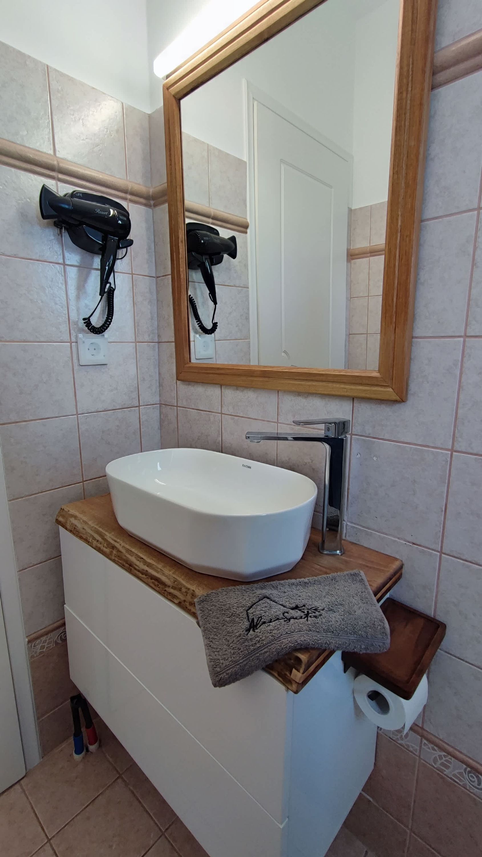 A bathroom with a white sink, a mirror, and two hair dryers mounted on the wall.