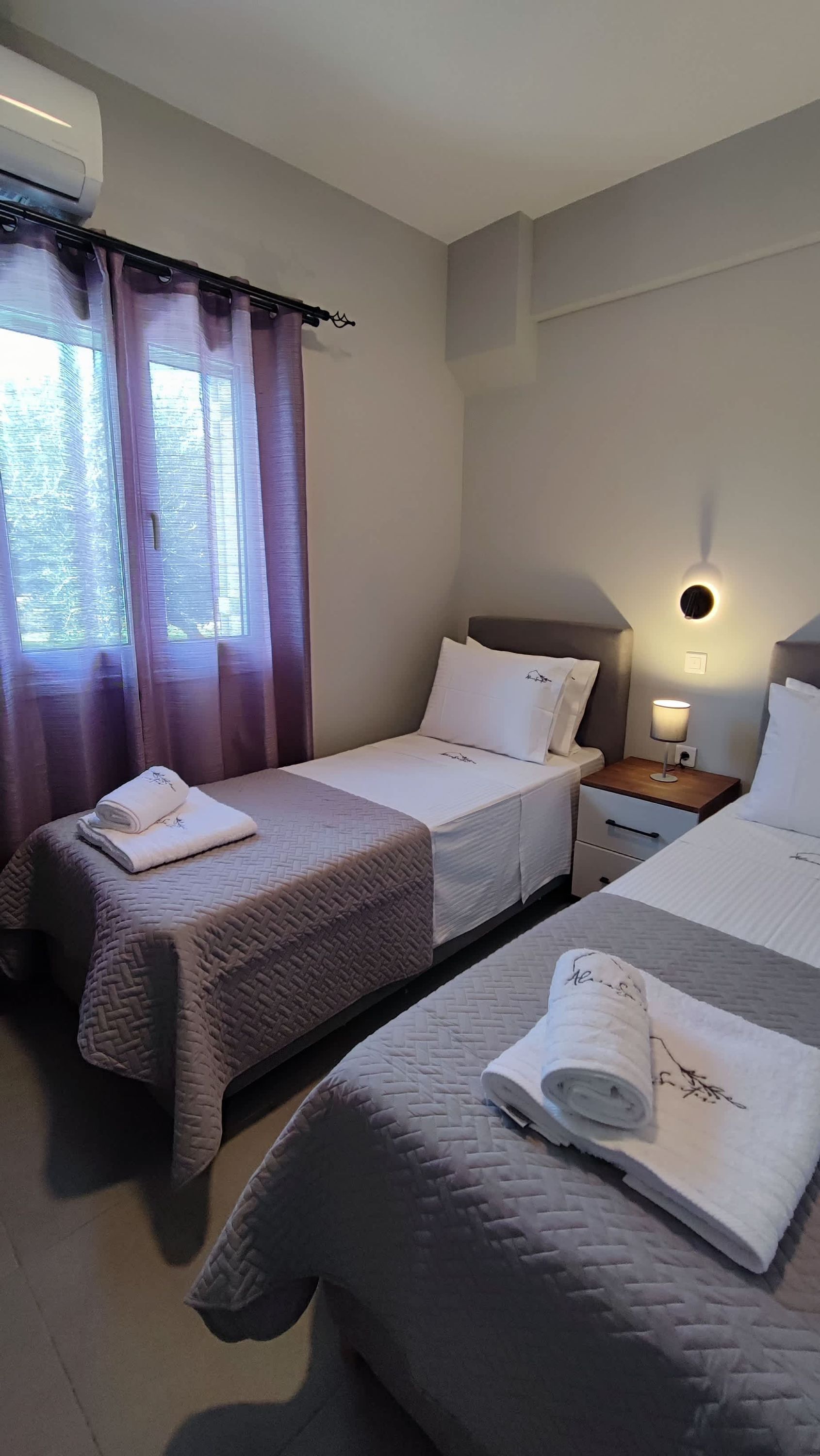 Une chambre d’hôtel avec deux lits, une table de chevet avec une lampe et un appareil de climatisation.