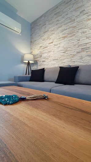 Ein Wohnzimmer mit grauem Sofa, einem Holztisch und einer Lampe.