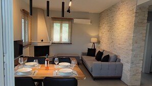 A modern living room with a dining area, a sofa, and a fireplace. - Alaia Kefalonia Garden Haven Elegant Holiday Home (Kefalonia)