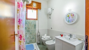 Un bagno con tenda doccia, water, bidet, lavabo e uno specchio.