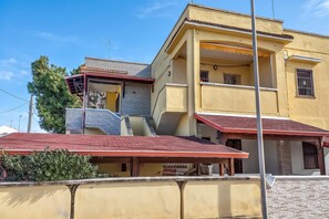 Edifício residencial com vários andares, teto vermelho, varanda e antena visível.