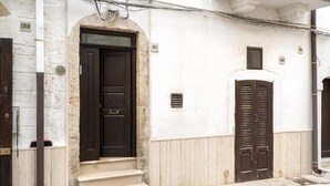 Un bâtiment avec une porte marron foncé, des marches de couleur beige et un mur blanc orné de fenêtres numérotées.