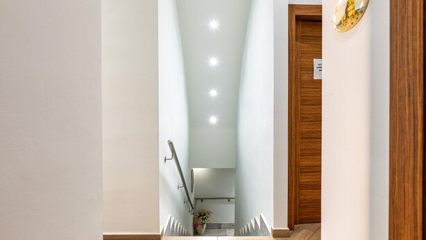 Un intérieur moderne avec une porte en bois, un mur blanc et un escalier menant à un niveau inférieur.