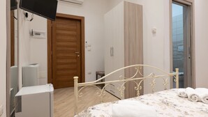 Une chambre à coucher comprenant un lit, une armoire, un téléviseur et un radiateur.