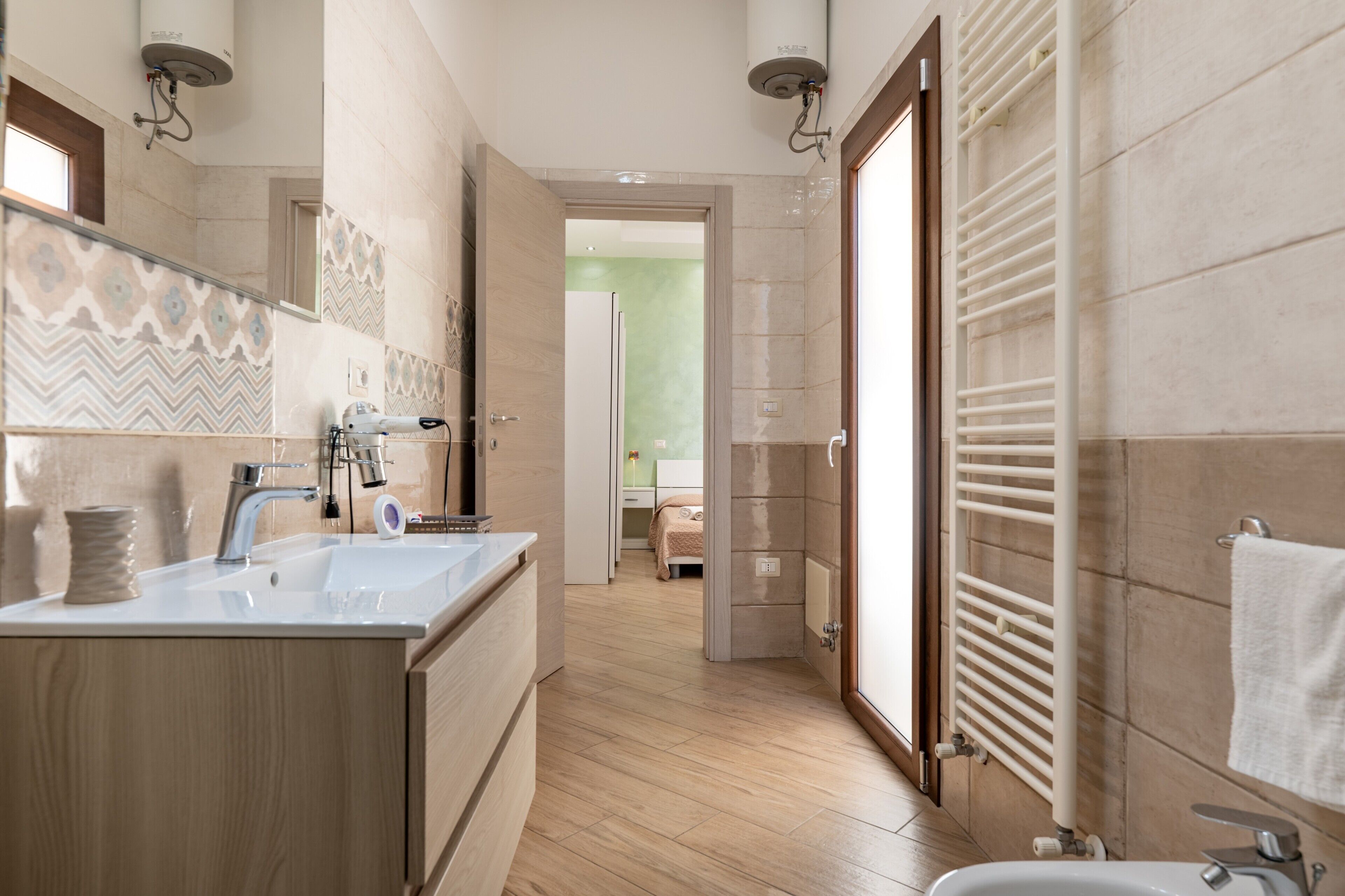 Une salle de bain moderne avec un double lavabo, un miroir, un porte-serviettes et un espace douche.