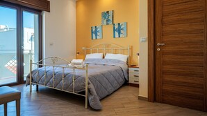 A bedroom with a bed, a wooden door, and a balcony.