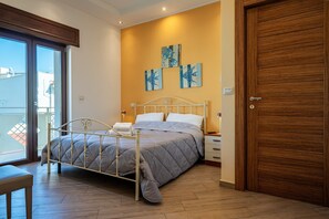 A bedroom with a bed, a wooden door, and a balcony. - Room 'Il Fenicottero - La Salina' with Wi-Fi and Air Conditioning (Avetrana)