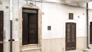 A building with a dark brown door, beige steps, and a white wall with numbered windows.