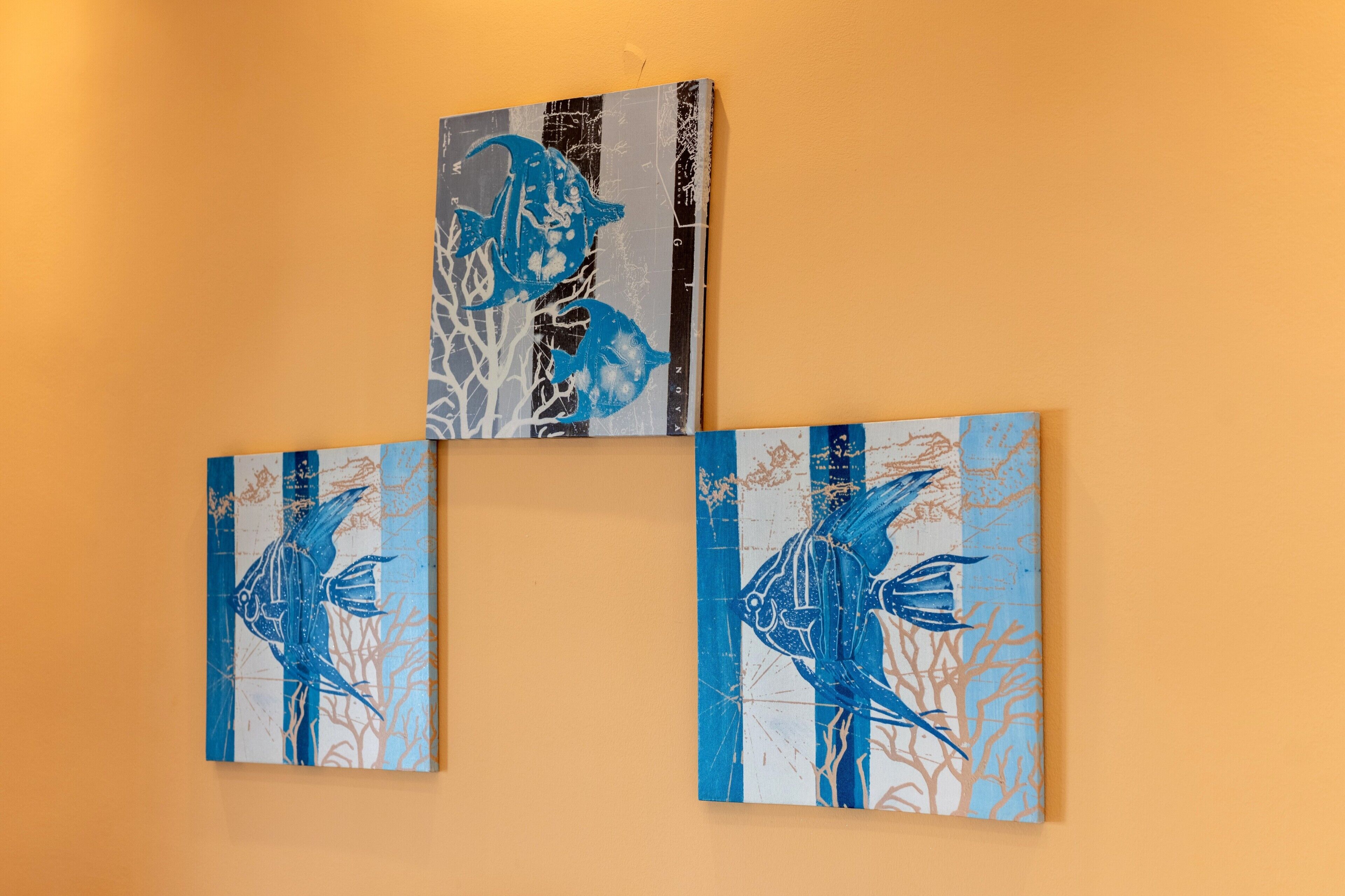 Three paintings of fish on a wall.