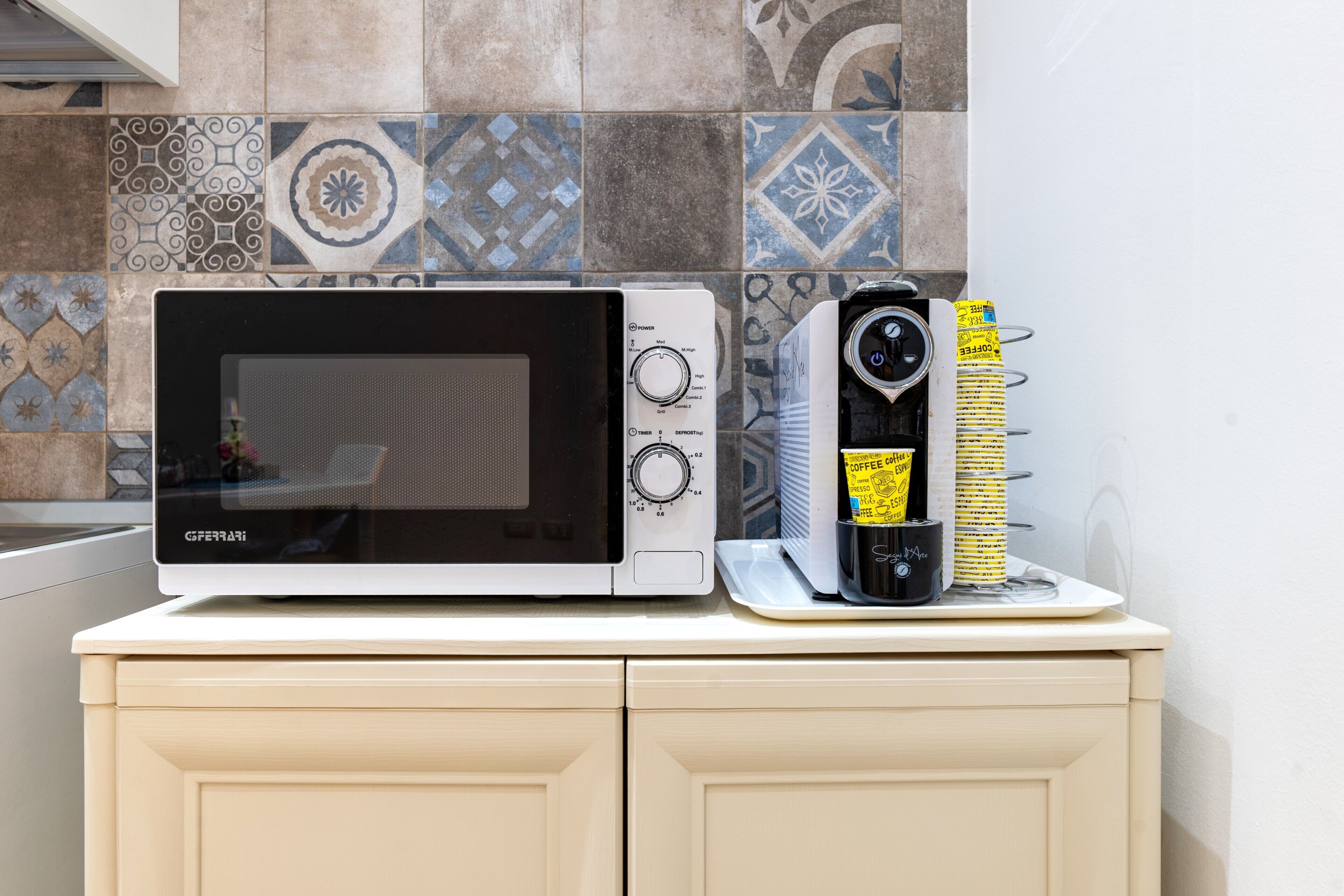 Une cuisine équipée d’un four à micro-ondes blanc, d’une machine à café et d’un plateau avec des tasses à café.
