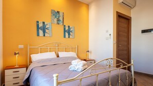 A bedroom with a bed, bedside lamps, a wooden door, and wall art.