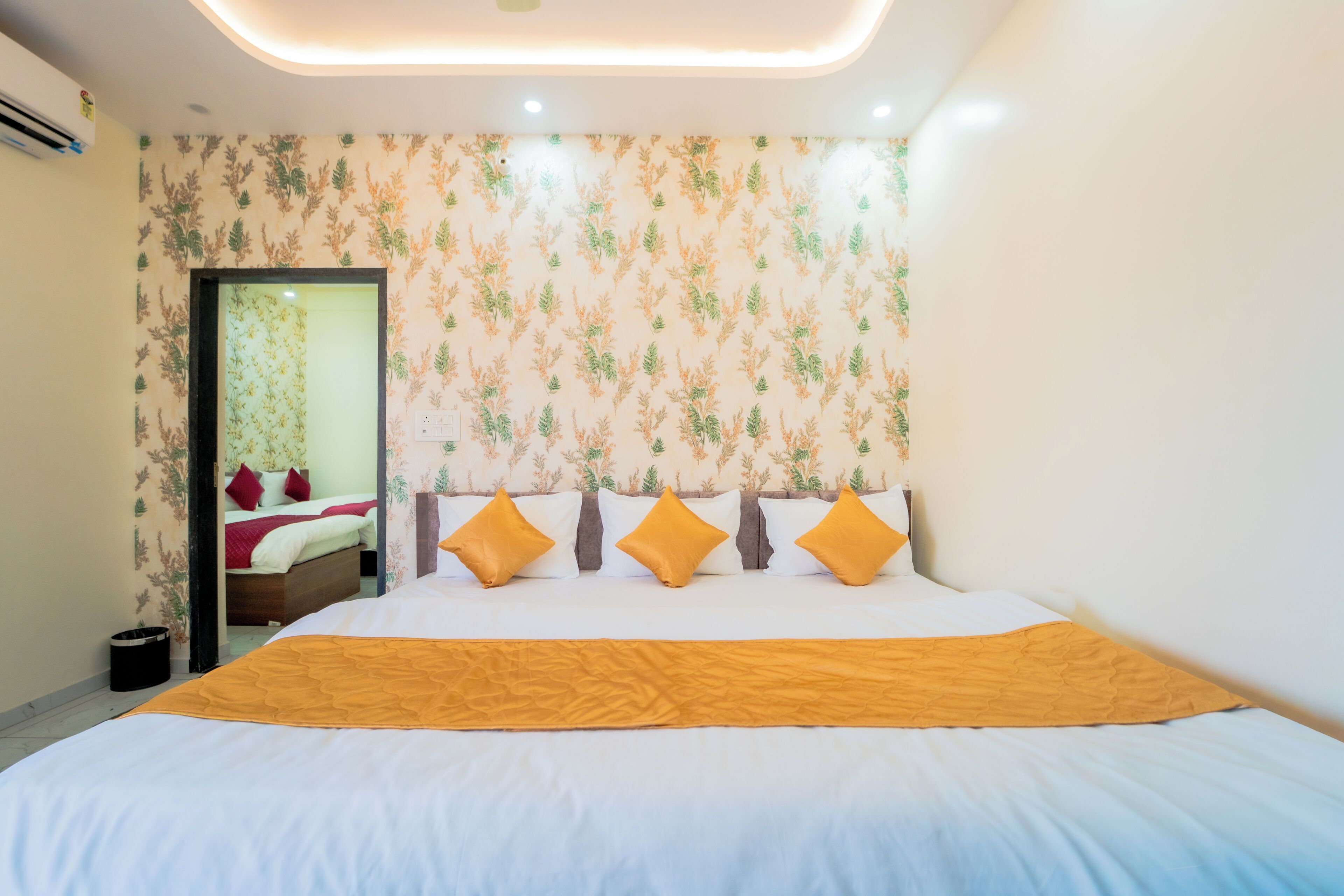 A hotel room with a large bed, a mirror, and a floral wallpaper design.