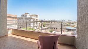 A balcony with a view of a cityscape, a wooden floor, and a pink chair. - Hotel Neel Kamal (Khatoo)