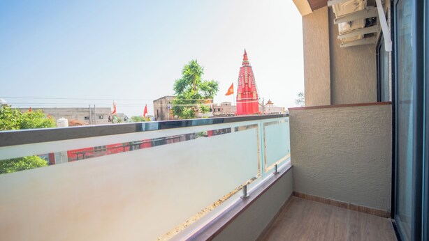 A balcony with a view of a building with a red spire, a clear sky, and a railing. - Hotel Neel Kamal (Khatoo)