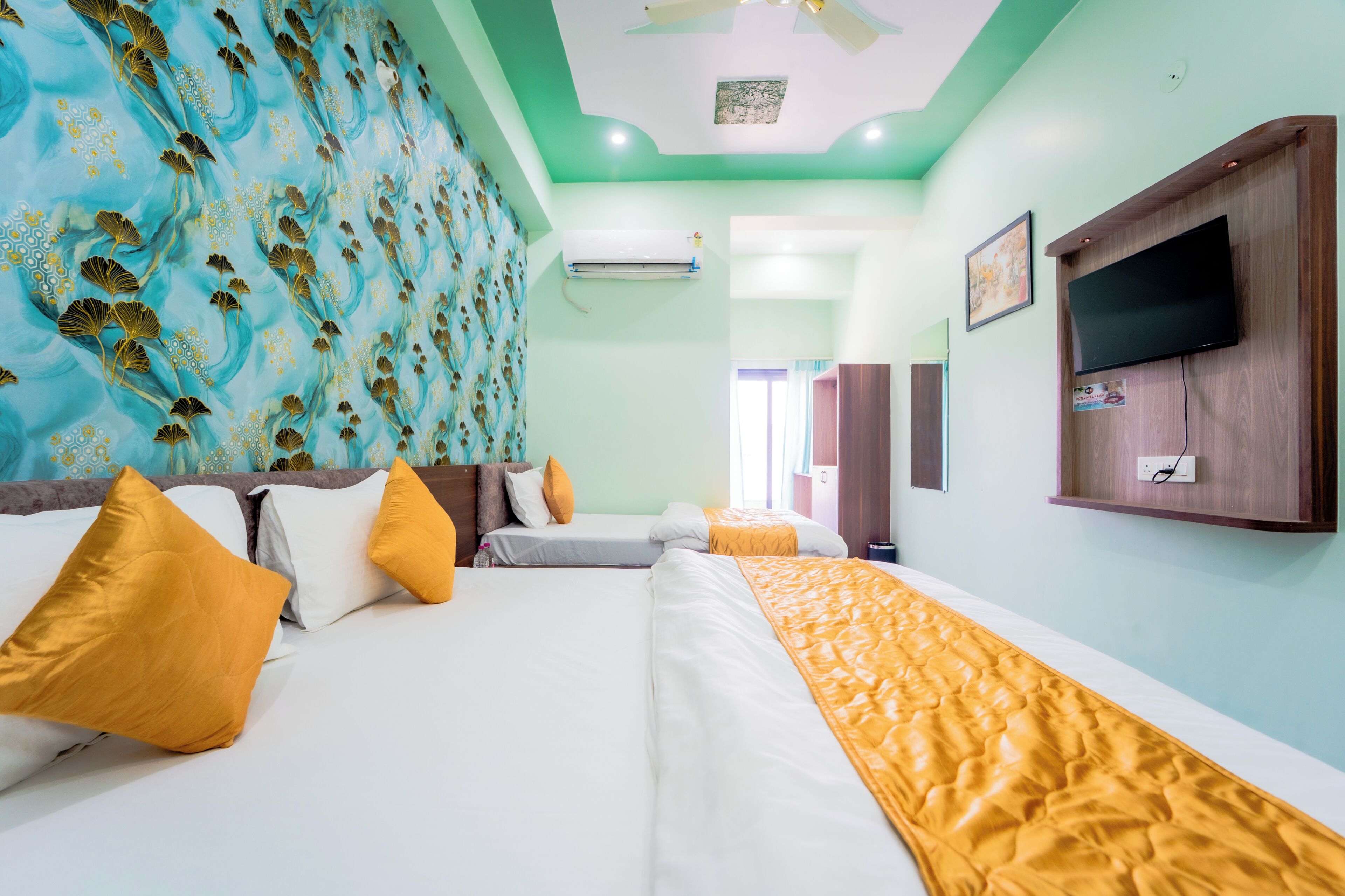 A hotel room with two beds, a television, an air conditioning unit, and a patterned wall.