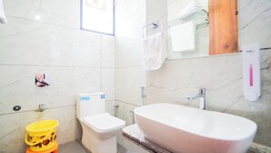 A bathroom with a toilet, a bathtub, and a yellow bucket. - Hotel Neel Kamal (Khatoo)