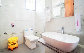 Un baño con inodoro, una bañera grande, un cubo amarillo y una pared de m ármol.