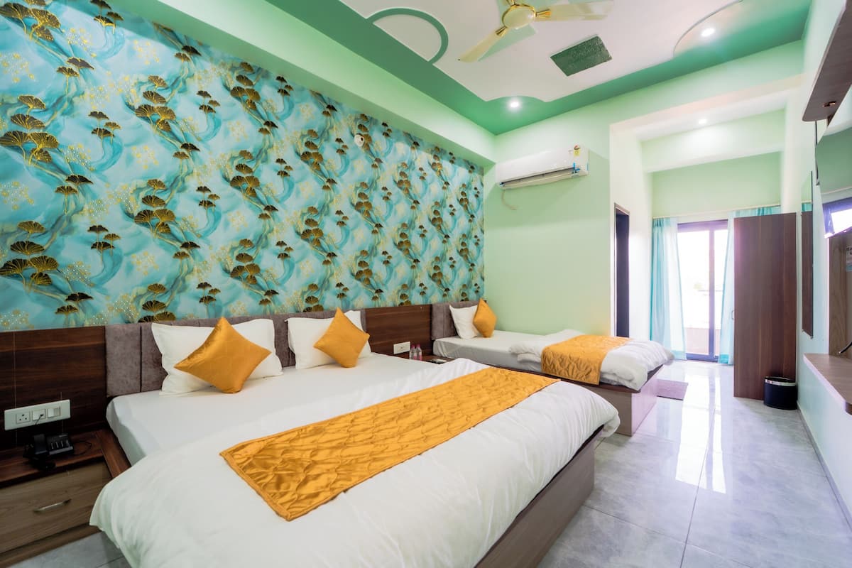 Habitación de hotel con dos camas, un papel tapiz estampado y un ventilador de techo.