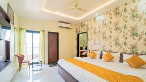 A hotel room with a bed, a chair, a table, and a ceiling fan. - Hotel Neel Kamal (Khatoo)