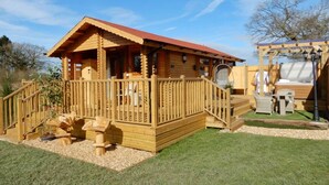 A wooden cabin with a porch, outdoor seating, and a pergola. - The Balmoral Studio Lodge – Private Hot Tub & On-Site Carp Fishing 🎣🛁 (Ellesmere)