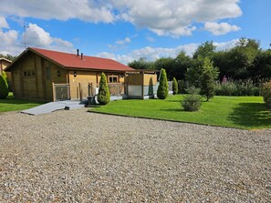 Une maison en bois avec un toit rouge, une allée en gravier et une pelouse bien entretenue.