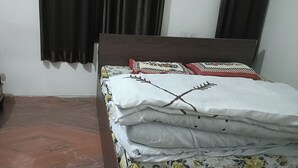 A room with a bed, a wooden chair, and a small table.