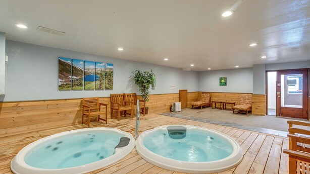 Un área de spa con dos jacuzzis, suelo de madera, asientos y decoración en las paredes.