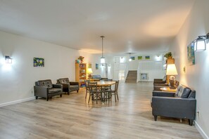 A spacious living area with a dining table, sofas, and a staircase leading to another level. - Heated Pool Access at Winter Park Base Camp! (Winter Park)