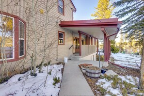 A house with a covered porch, a snow-covered yard, and a wooden deck. - Heated Pool Access at Winter Park Base Camp! (Winter Park)