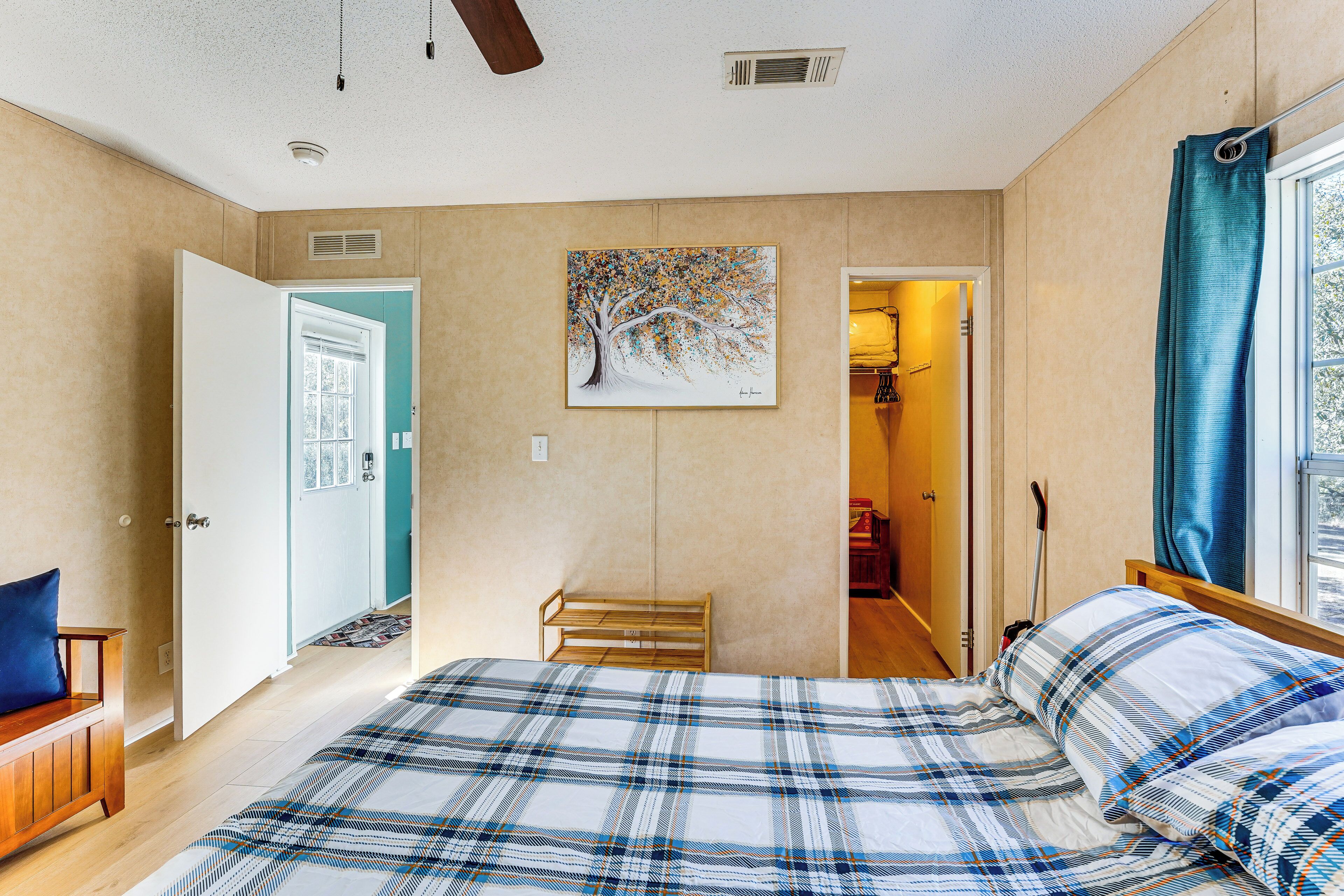 Un dormitorio con una cama, un banco, una puerta y un cuadro en la pared.