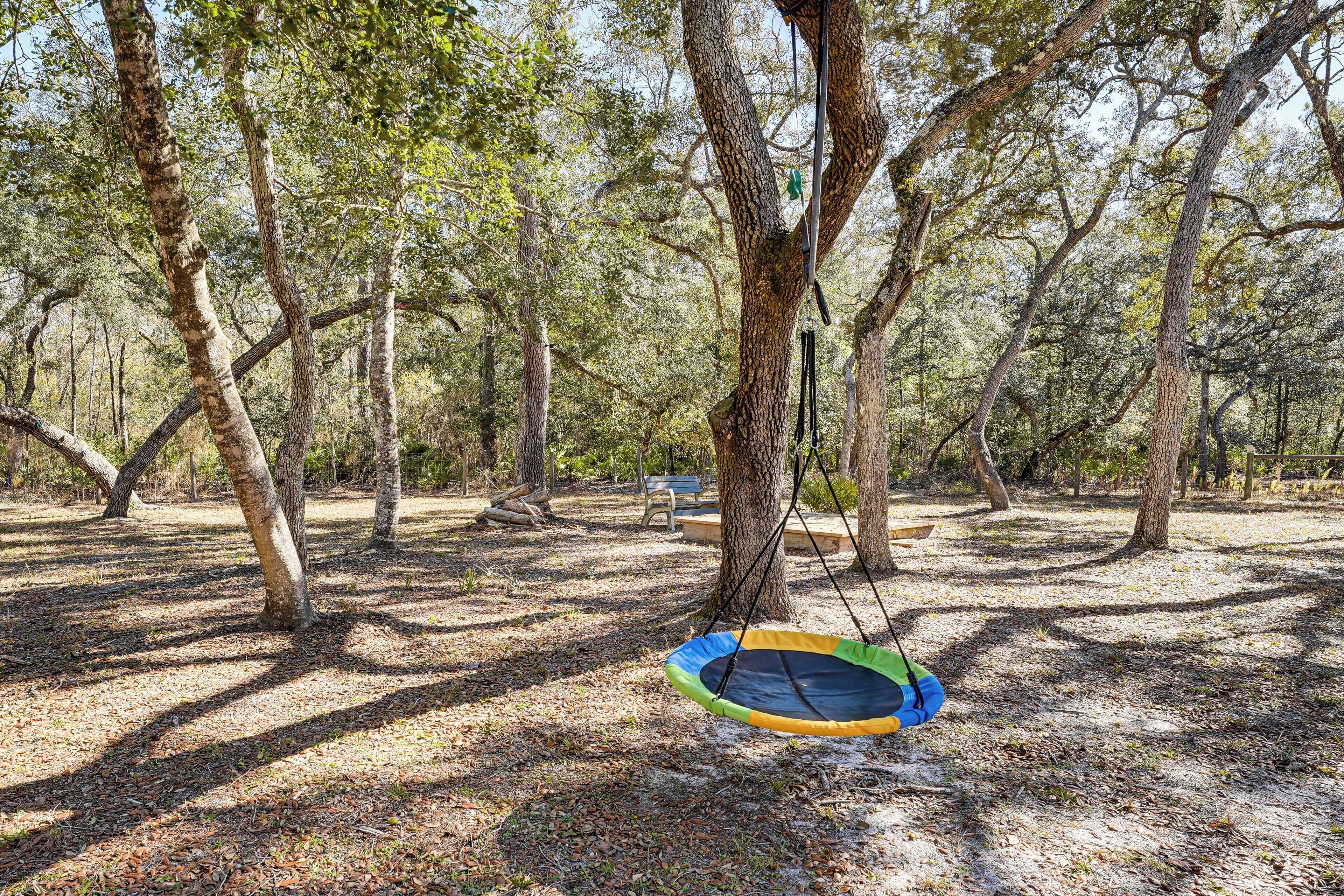 A hammock swing hanging from a tree in a wooded area.