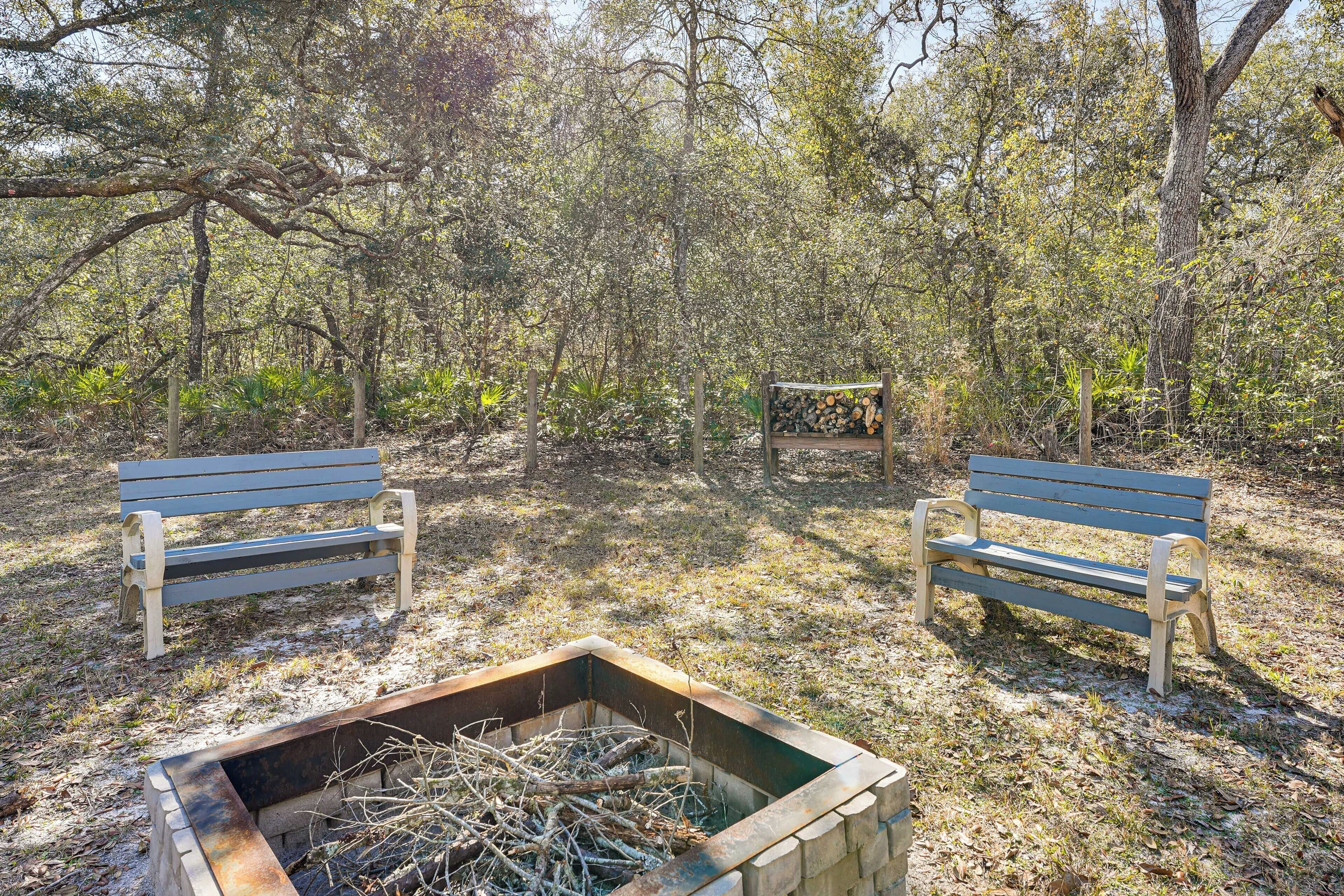 Two wooden benches in a natural setting with a fire pit in the foreground.