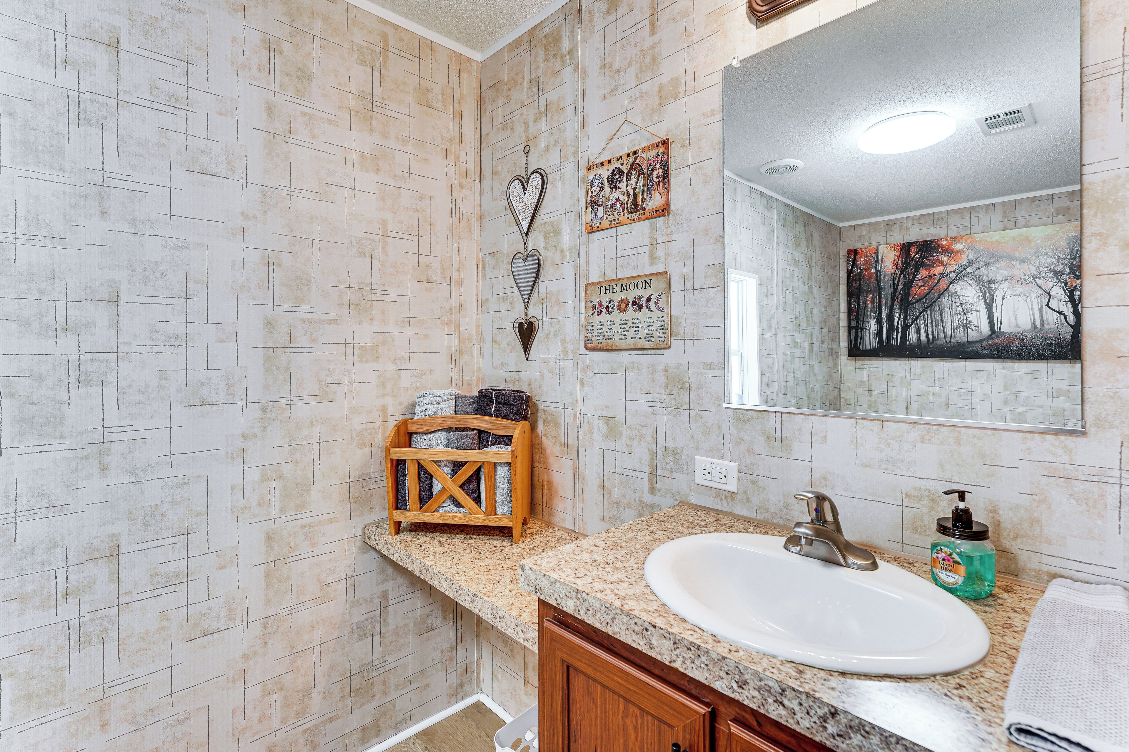A bathroom with a white sink, wooden towel rack, and a mirror.