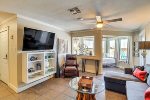 A living room with a television, a brown leather chair, a glass coffee table, and a grey sofa. - Walk to Beach! Pet-friendly Mustang Island Retreat (Port Aransas)