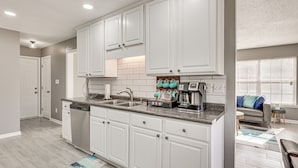 Una cocina moderna con armarios blancos, encimera de granito y lavavajillas integrado.