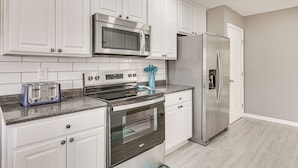 Una cocina moderna con armarios blancos, electrodomésticos de acero inoxidable, un tostador y un microondas.