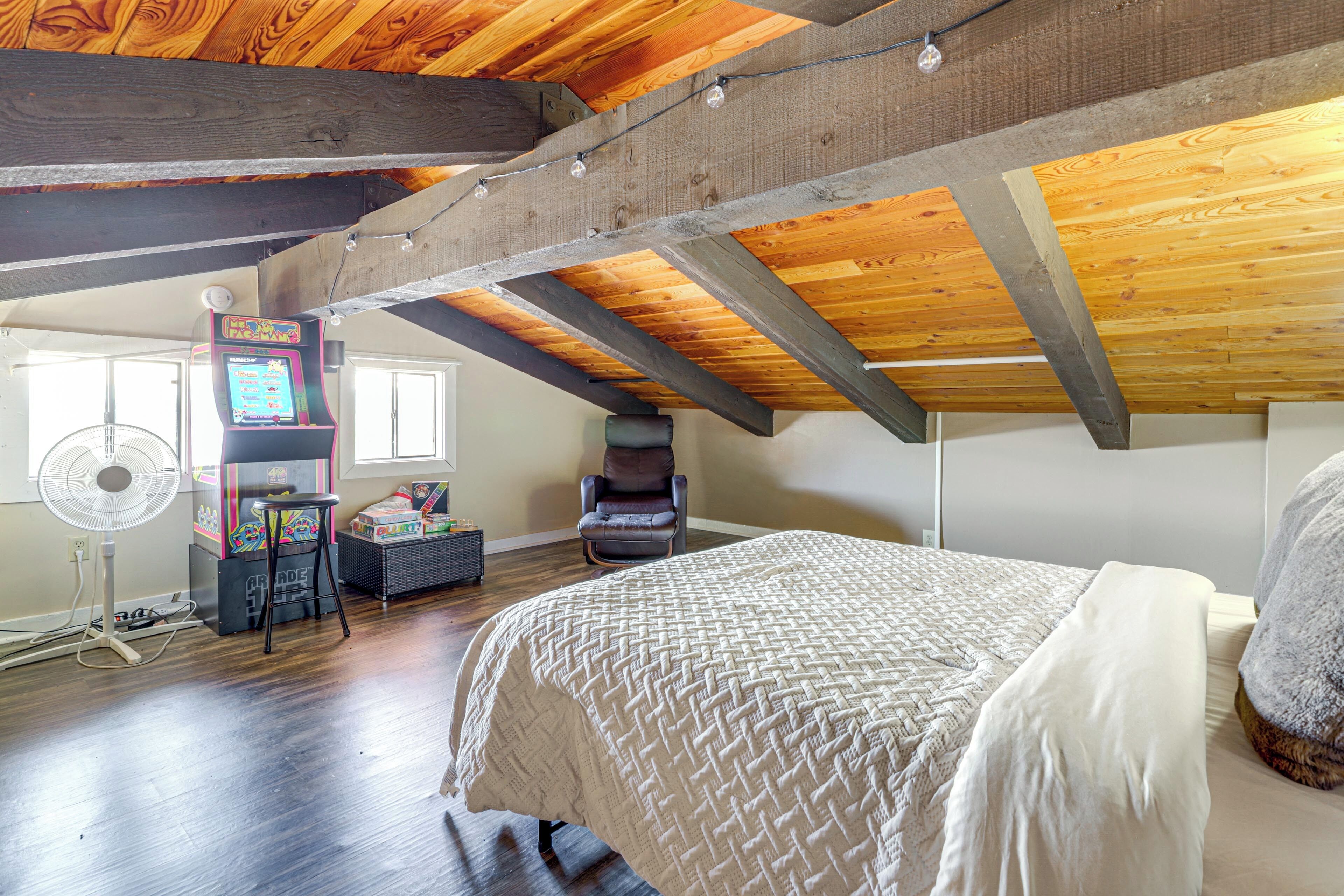 Una camera da letto con un letto grande, travi in legno, una ventola e una console per videogiochi.