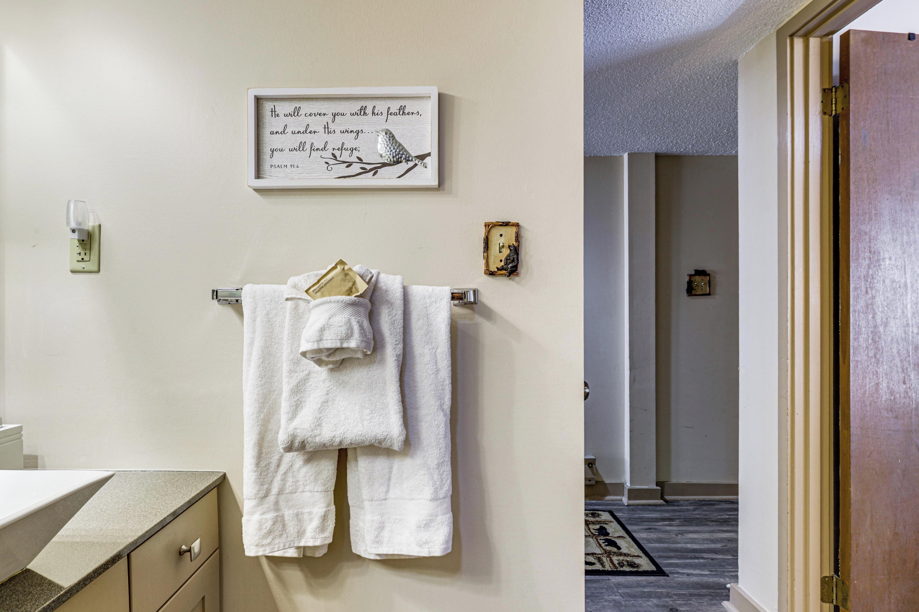 Une salle de bain avec une serviette blanche suspendue à un porte-serviettes, une citation inspirante encadrée et un petit objet décoratif accroché au mur.