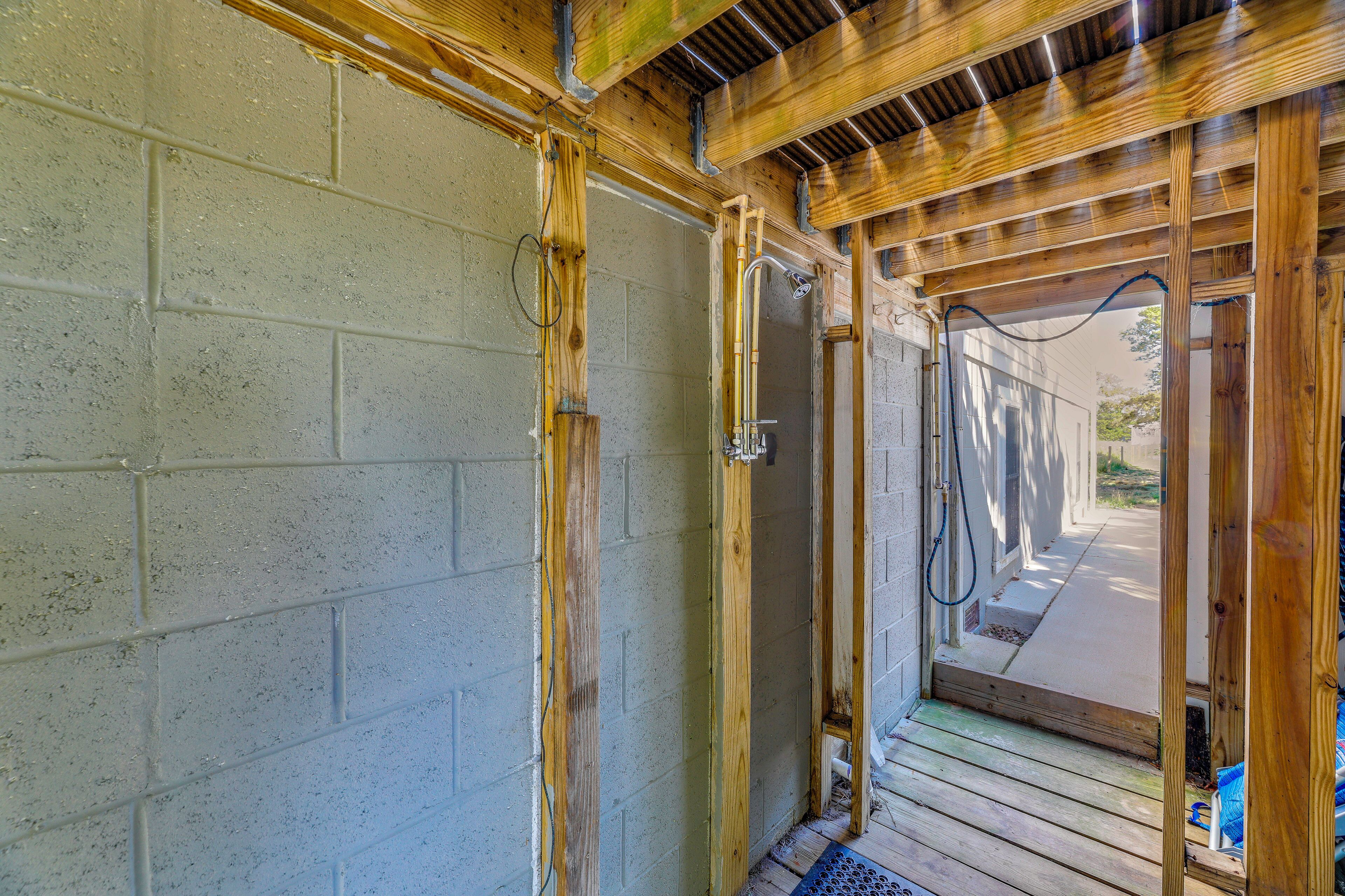 Eine Holzkonstruktion mit Duschbereich, einer Betonwand und einem Holzboden.