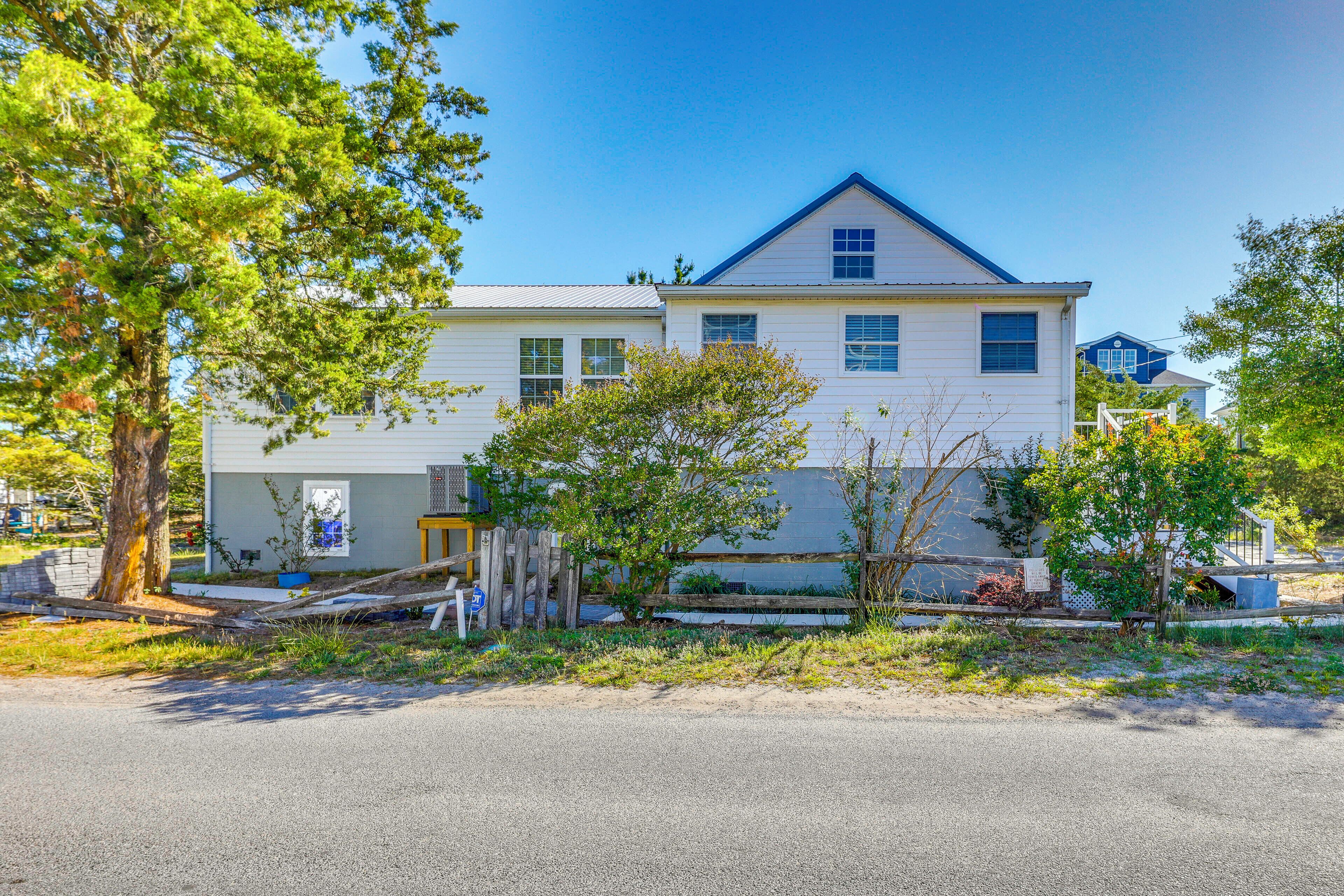 A two-story house with a gabled roof, a garage, and a front yard with trees and a fence.
