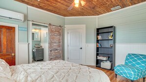Ein Schlafzimmer mit einem großen Bett, einem Kleiderschrank, einer Kommode, einem Bücherregal und einem Sessel.